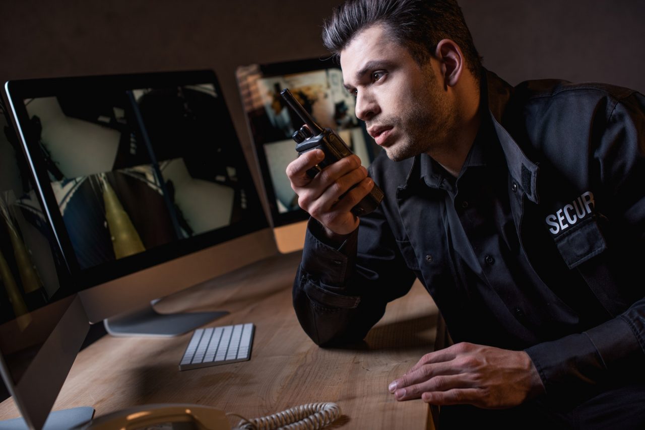 handsome-guard-in-uniform-talking-on-walkie-talkie-at-workplace.jpg